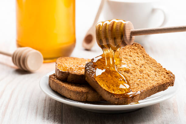 Honey dripping from wooden dipper on some wholemeal rusks.